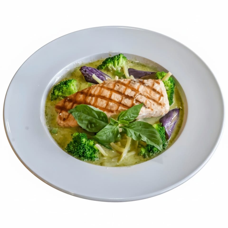 Grilled salmon in green curry with broccoli, purple eggplant, and basil in a white bowl.